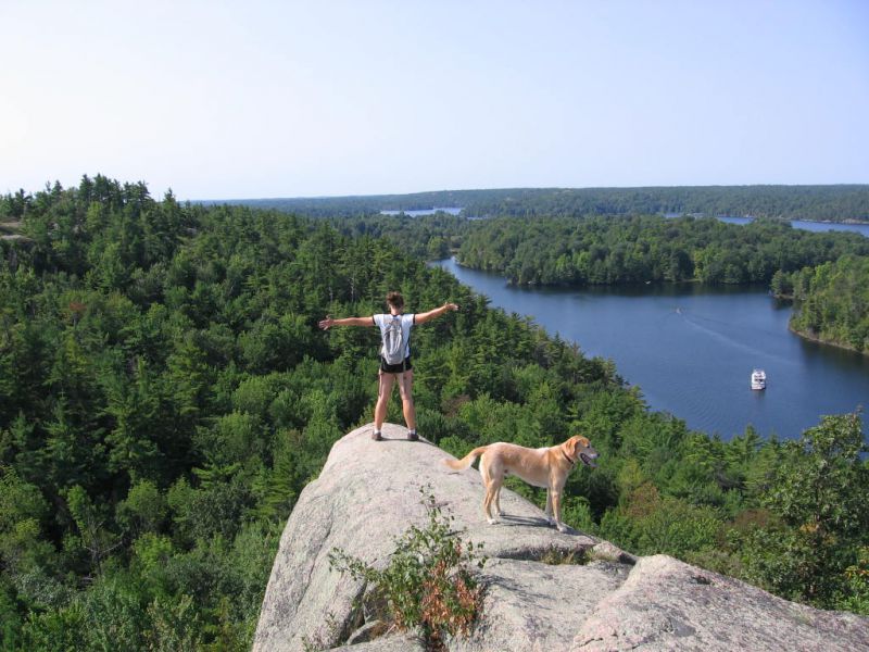 Woman and dog atop Rock Dunder looking out over the treetops